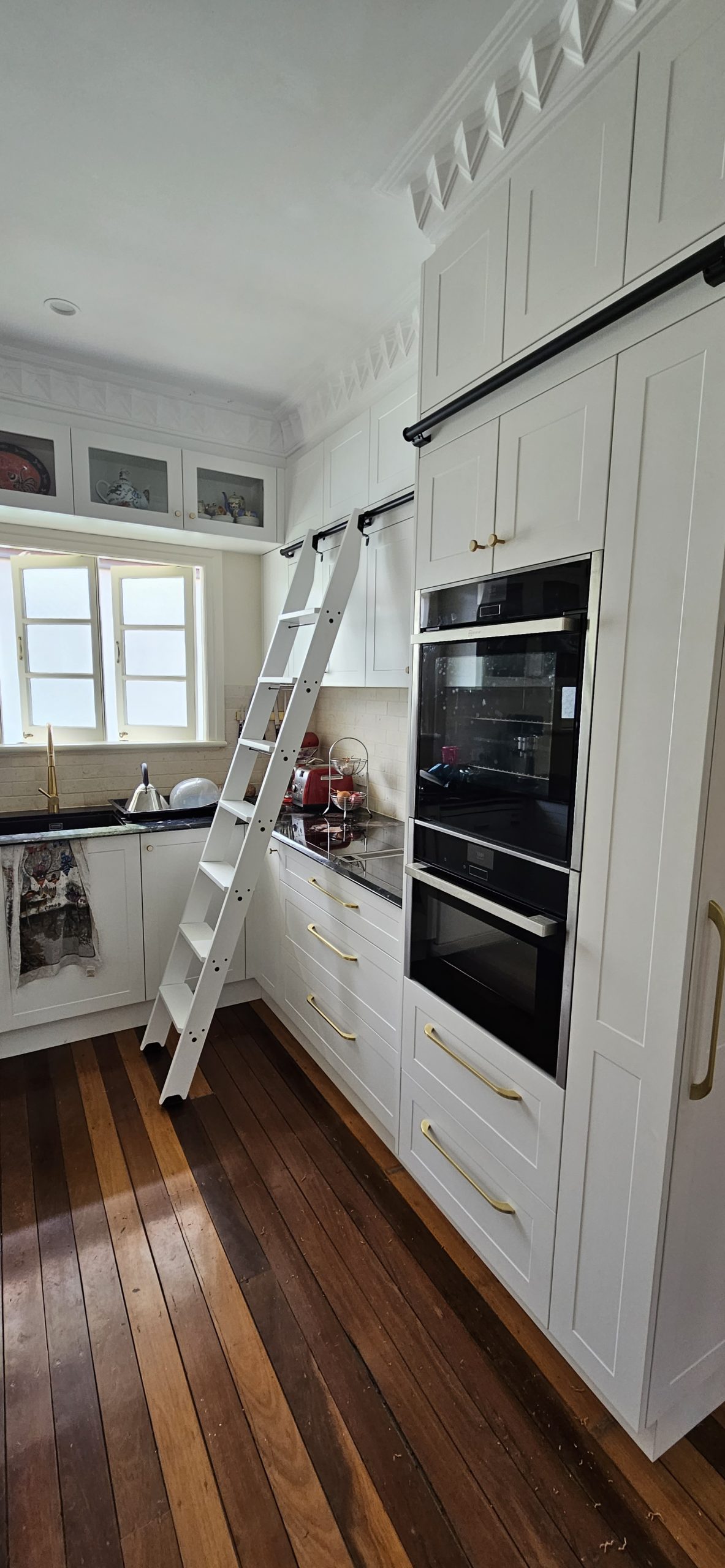 Fixed library ladder in kitchen, finished in white 2-pack coat and black Quiet Glide Hardware - Access Ladders Qld